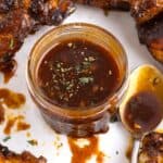 Chipotle honey sauce in a jar surrounded by pieces of chicken.