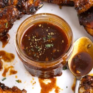 Chipotle honey sauce in a jar surrounded by pieces of chicken.