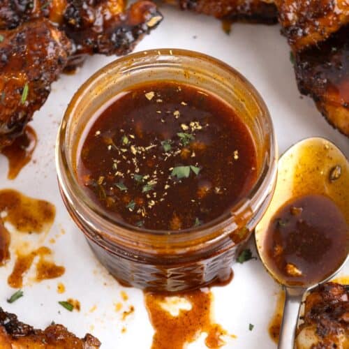 Chipotle honey sauce in a jar surrounded by pieces of chicken.
