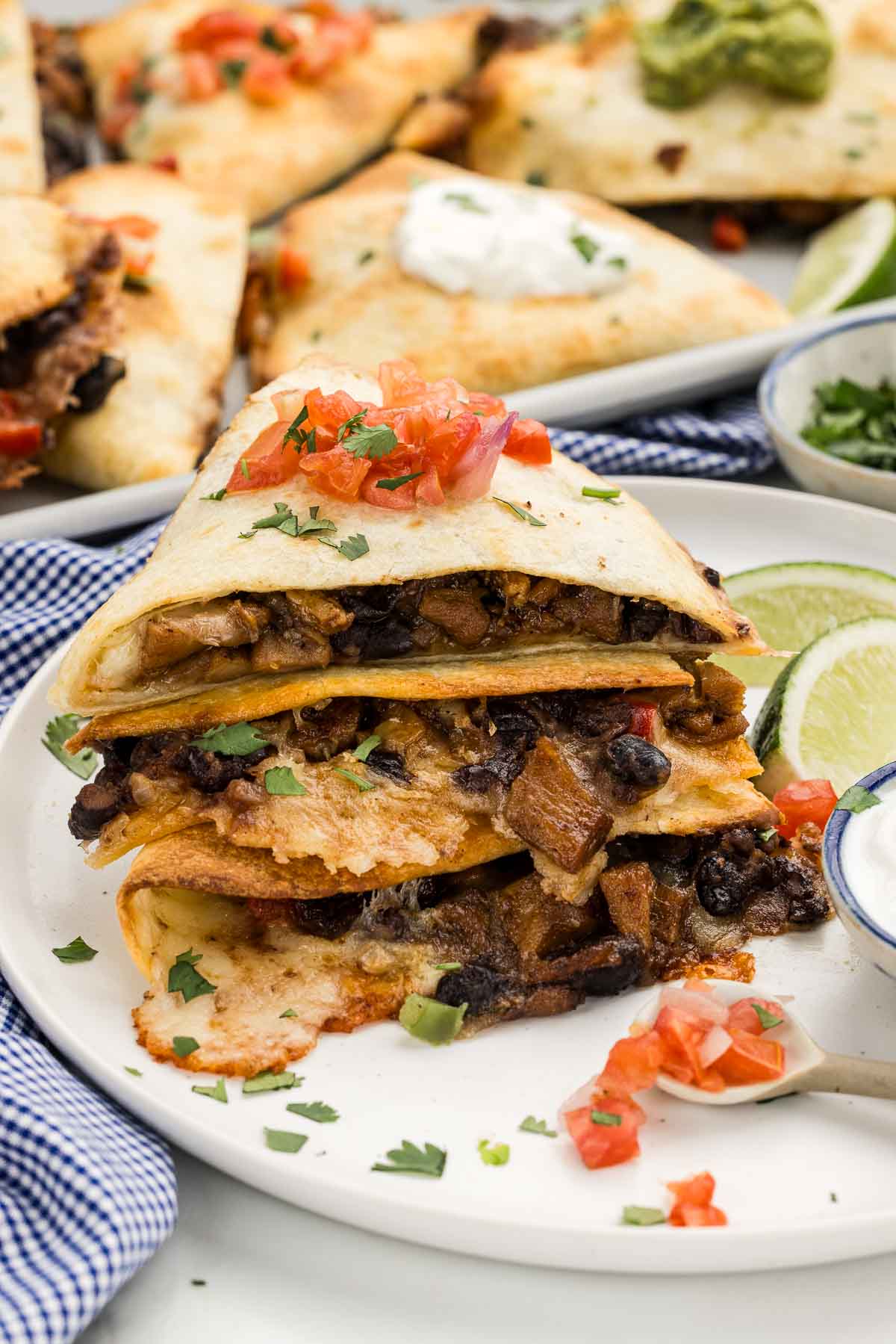 Quesadilla triangles stacked on top of each other on a white plate.