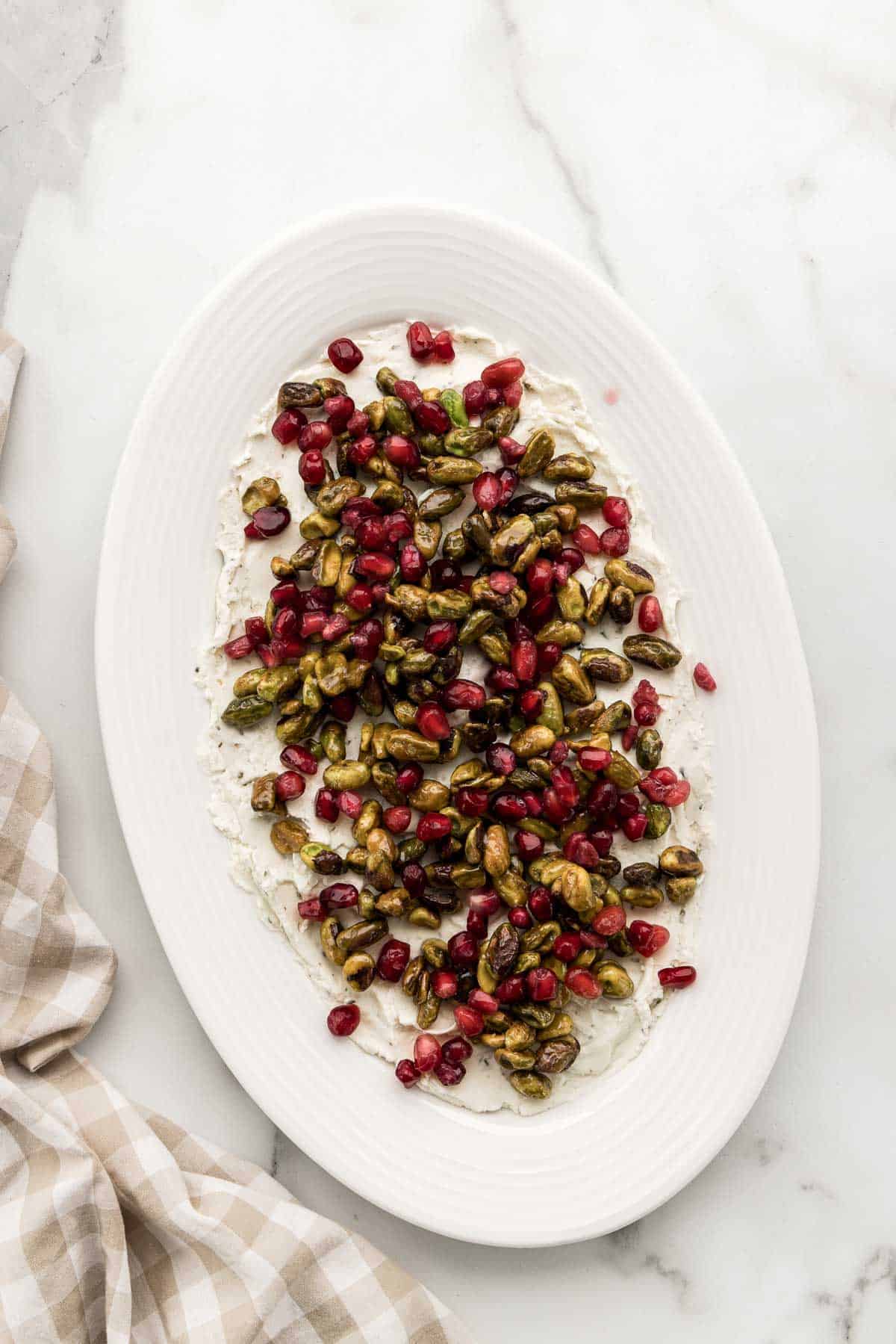 An oval dish of boursin dip with pomegranates.