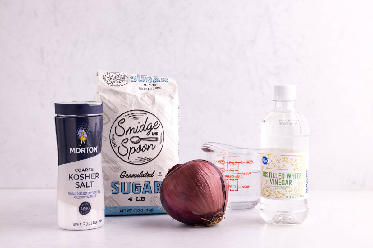 Salt, sugar, onion, water, and white vinegar on a countertop.