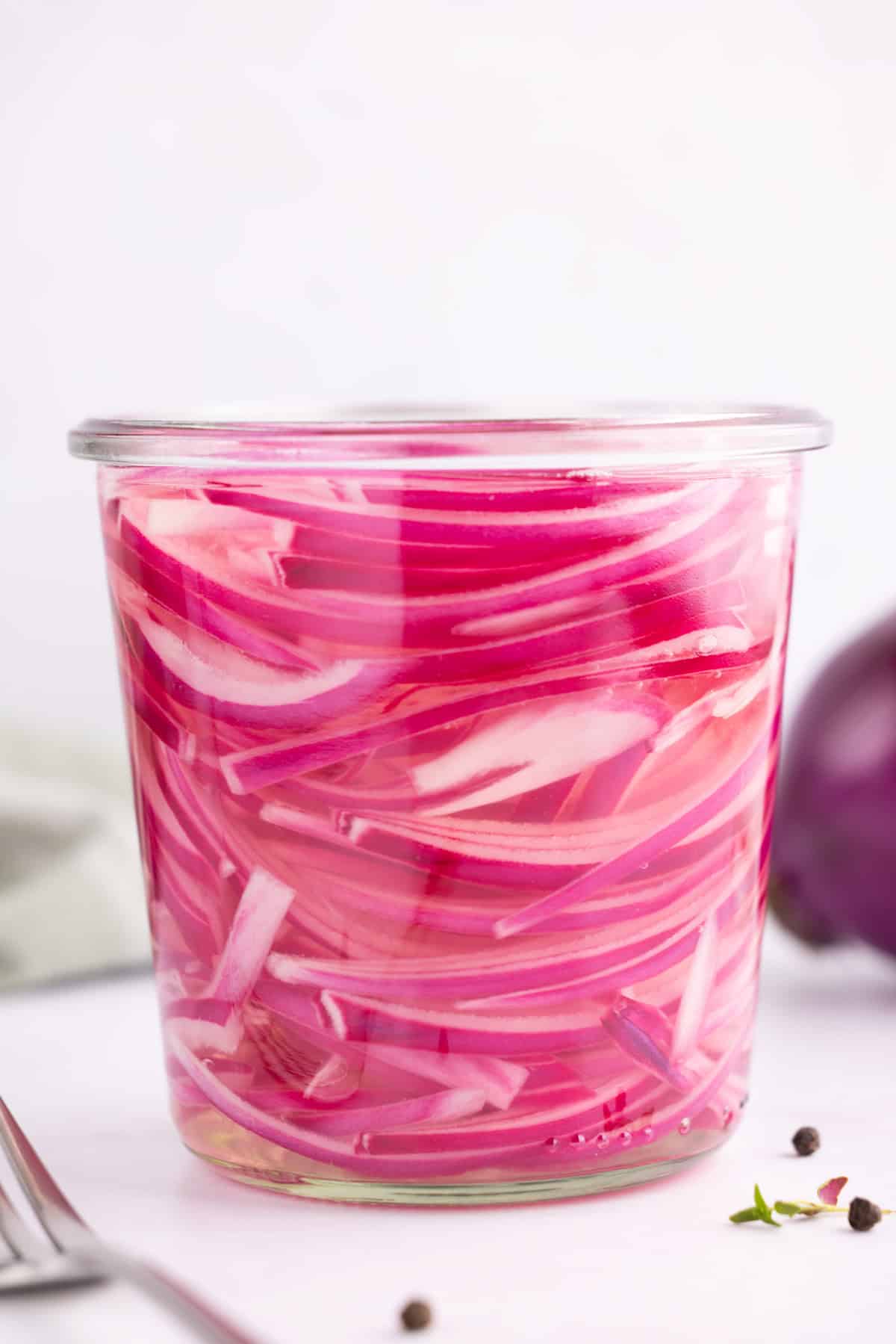 Side view of pickled red onions in a glass jar.