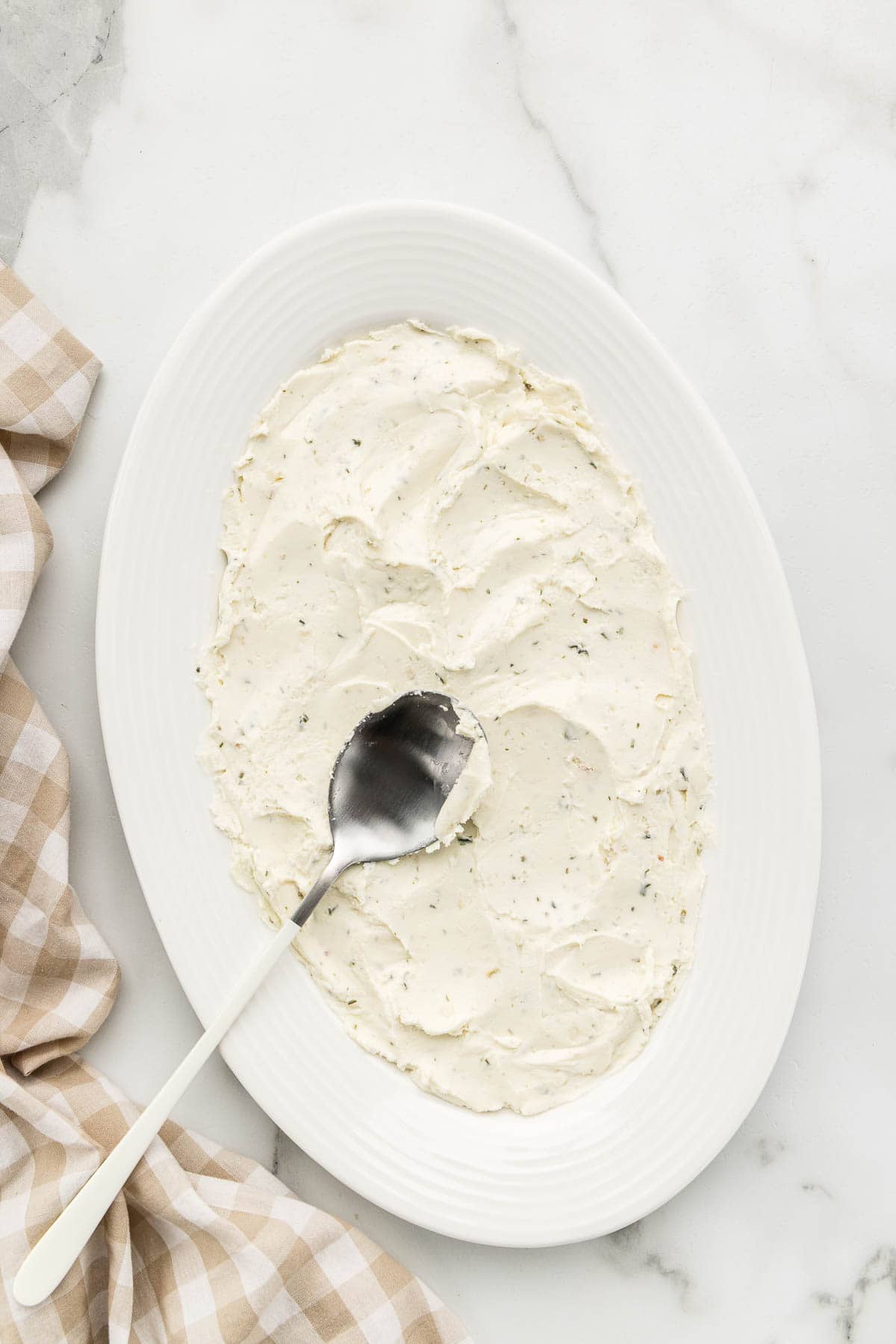 Packing boursin dip into a serving dish with a spoon.