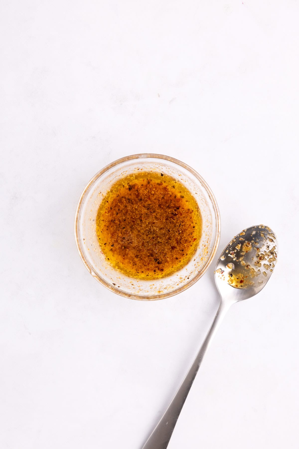 A small glass dish of garlic butter with a spoon.