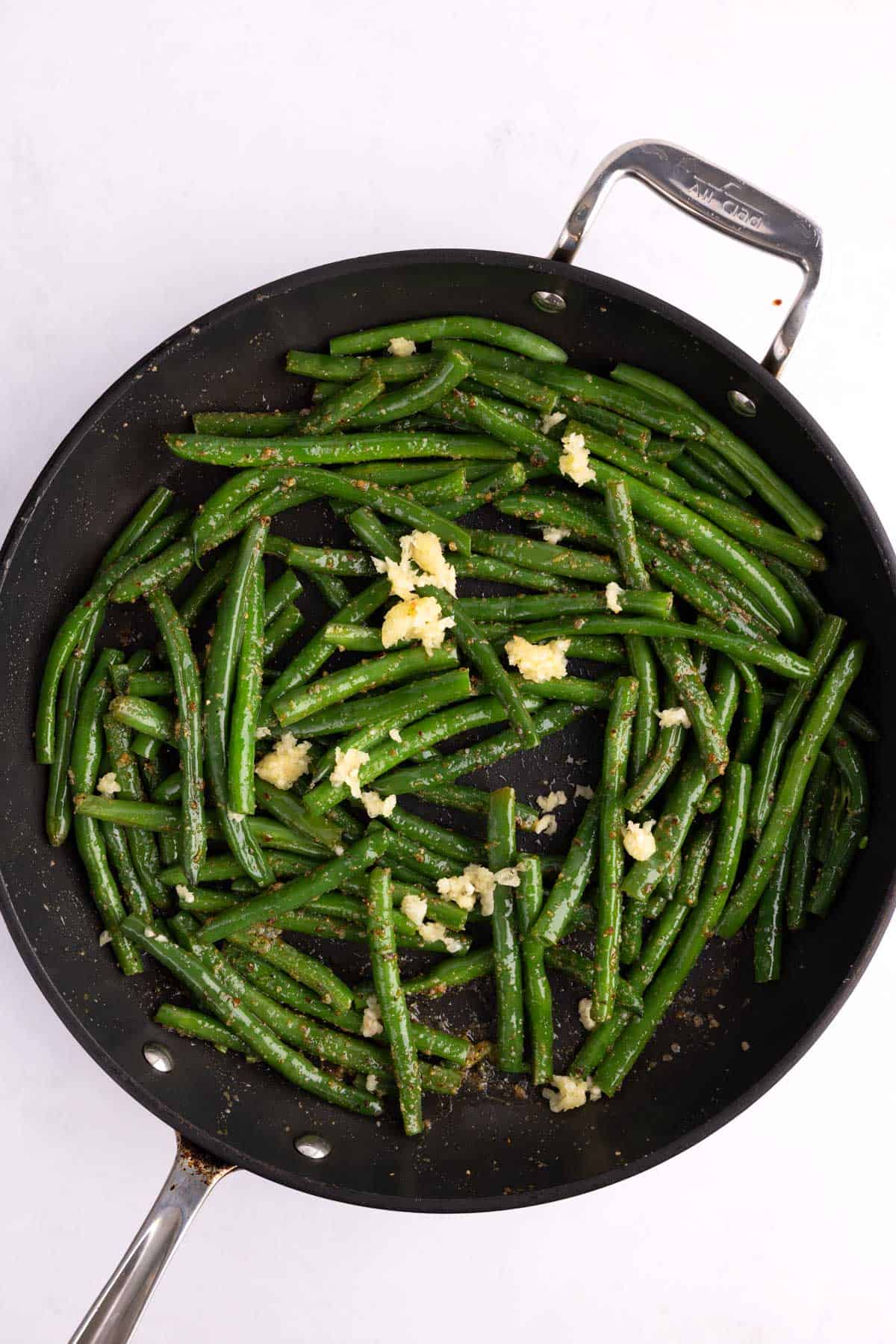 Garlic added to a skillet of green beans.
